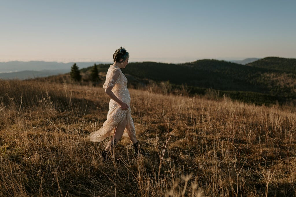 A girl walks through a field showing off her shimmery elopement wedding dress.