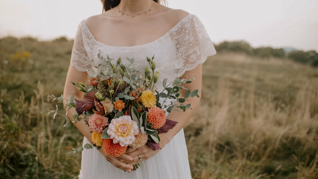 A close up shot of a bouquet being held by a bride during her elopement in a big field of high grass.