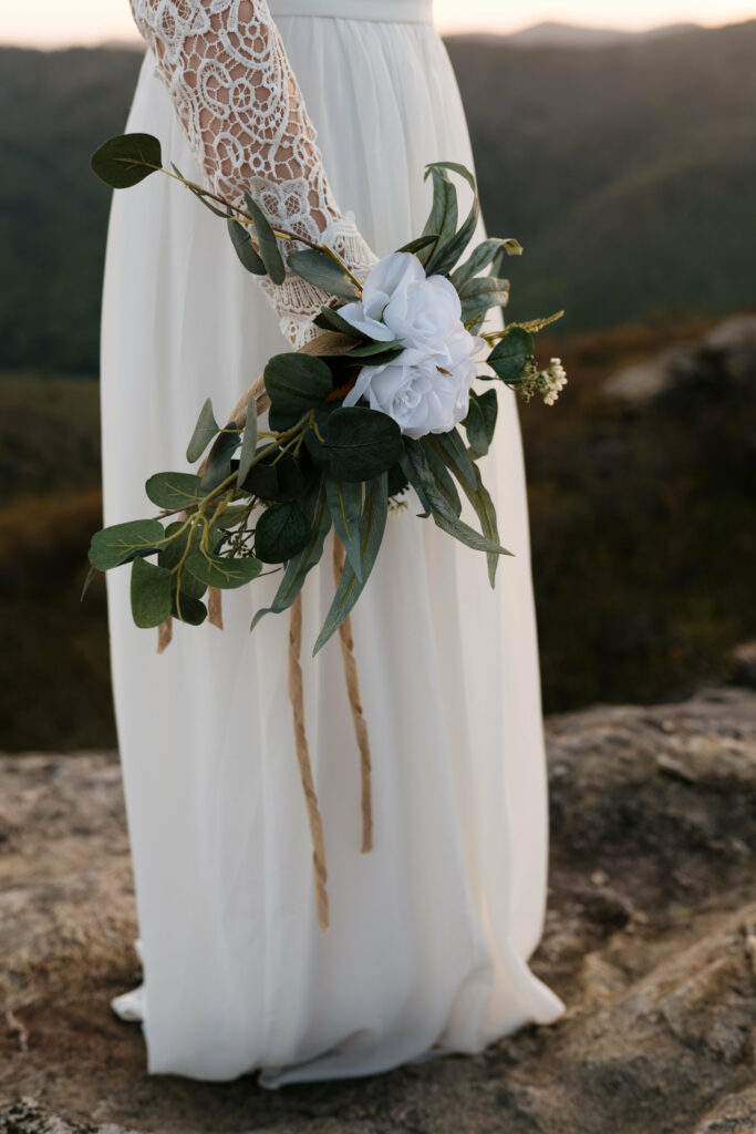 A silk floral wristlet on a bride in nature on a mountain in NC.