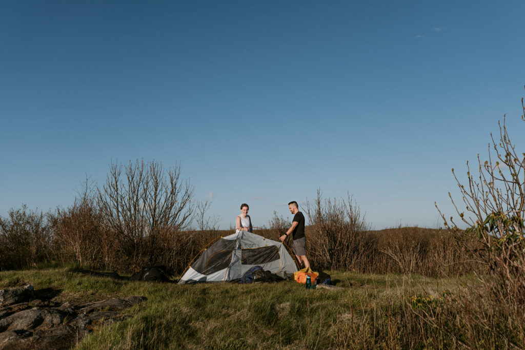 A couple sets up a tent on a mountaintop during their backpacking elopement in NC.