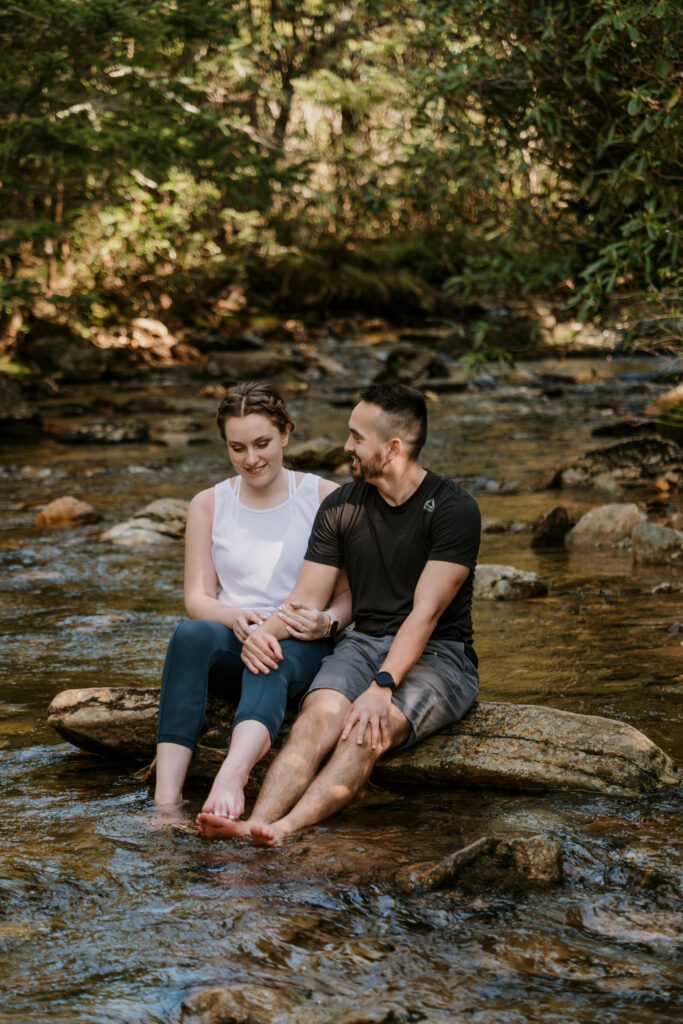 A couple sits on a rock in the middle of the river in NC.