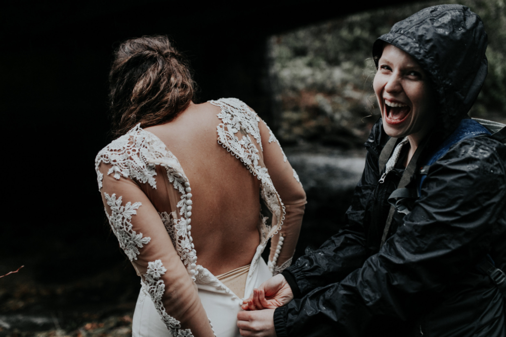 Elopement photographer and videographer helps bride get dressed during her Washington Elopement
