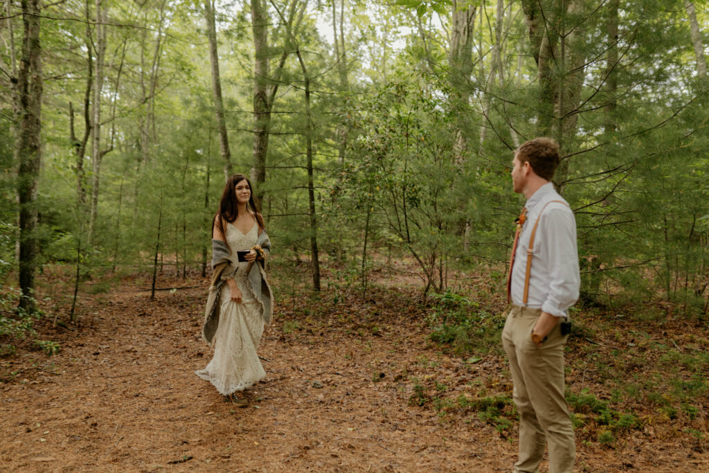 A bride walks up to her groom before their ceremony for their elopement in a North Carolina forest.