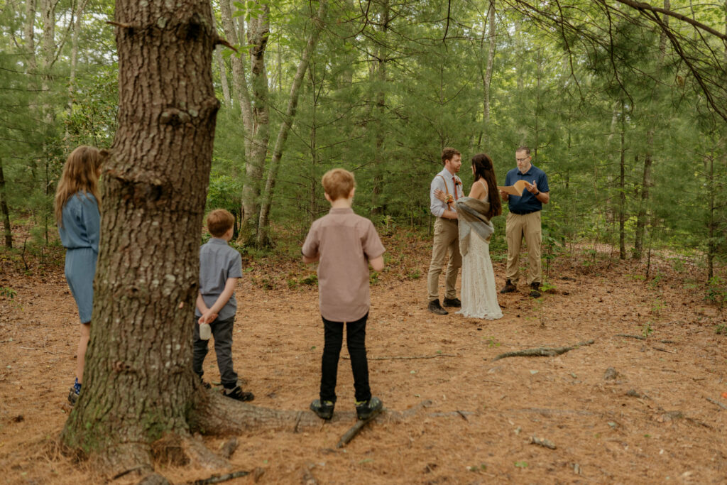 A bride and groom are standing in front of a few family members during their ceremony for their elopement in a North Carolina forest.