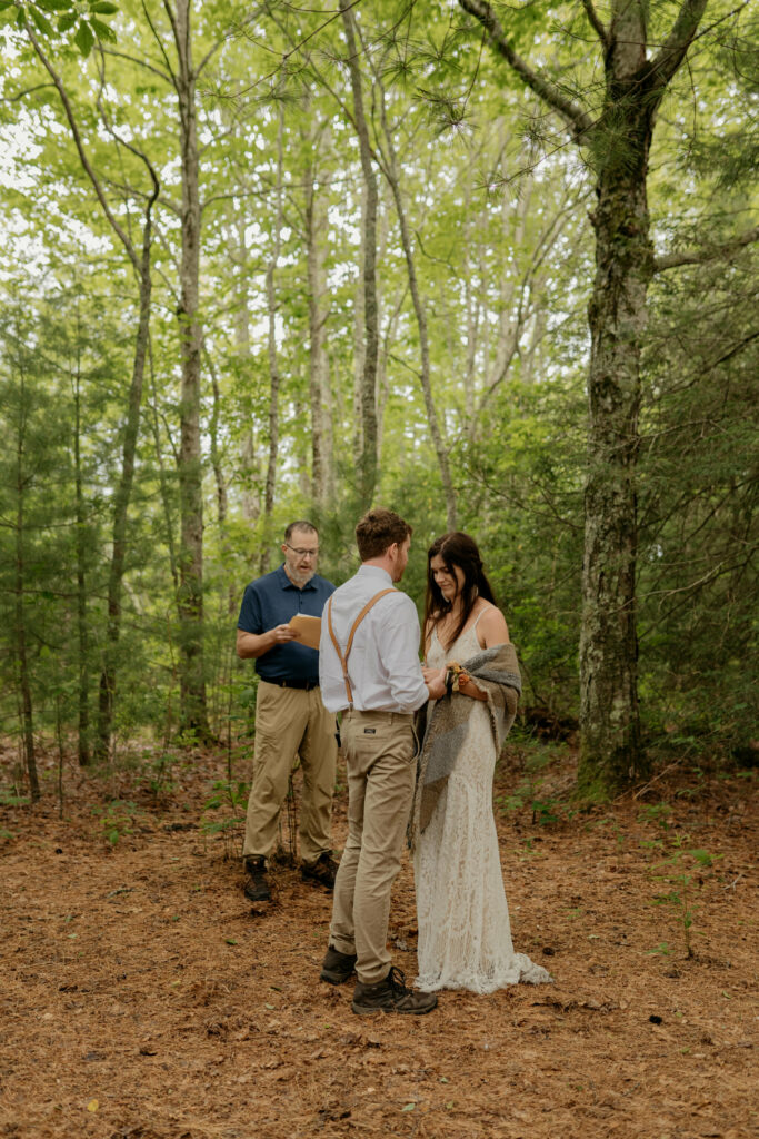 A bride and groom are standing together during their ceremony for their elopement in a North Carolina forest.