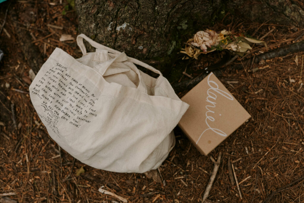 Details of a bag that has a hand written letter on it, and box that reads “Daniel” and a floral wristlet all sit on the ground.