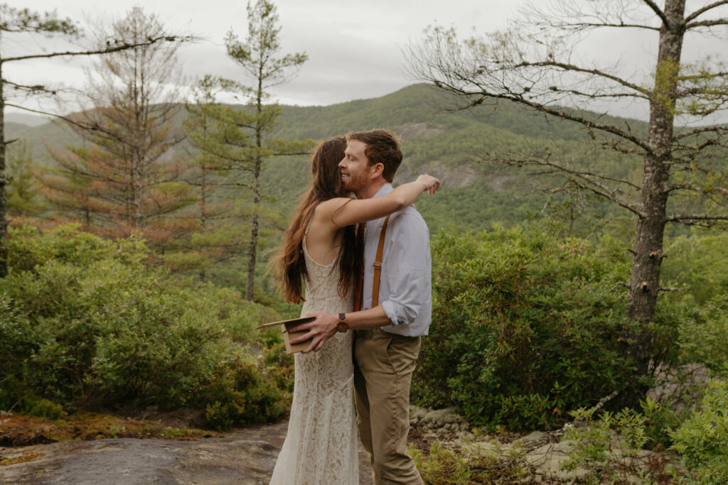 A couple is in a forest in North Carolina during their elopement. They are hugging after their first look moment and the groom is smiling.