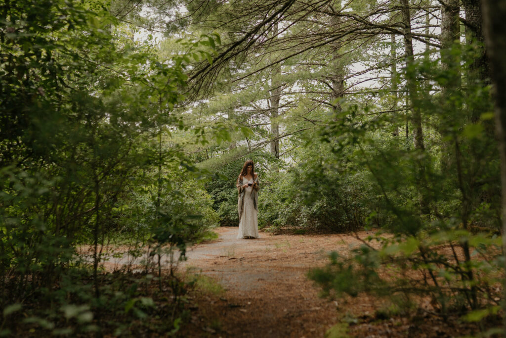 A bride is standing in the forest reading over her vows before her elopement ceremony in North Carolina.