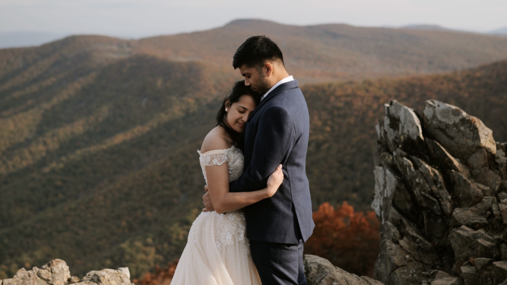 A couple stands hugging in front of the Shenandoah National Park mountains in their wedding clothes during the fall.