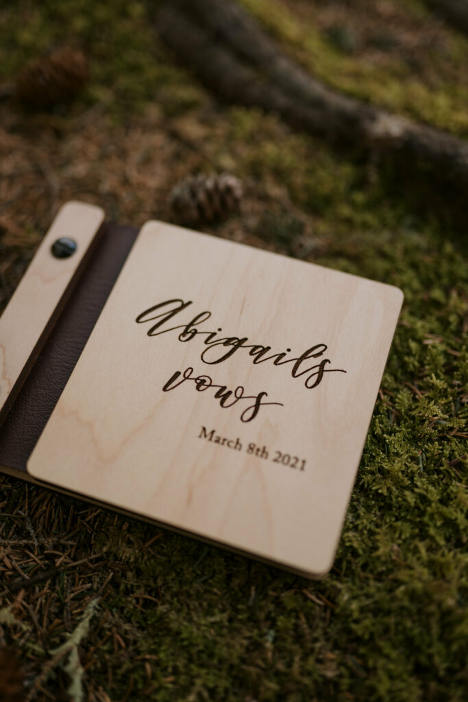 A wooden book that says “Abigail’s Vows” sits on a bed of moss.