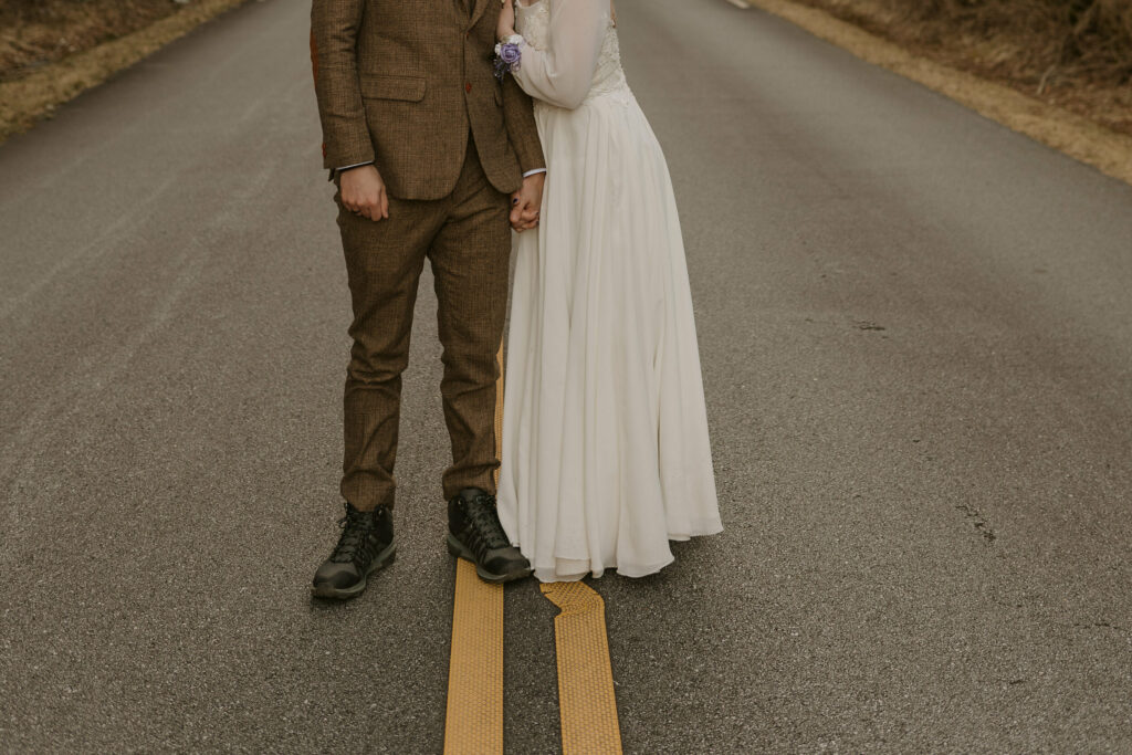 Closeup of a woman in a wedding gown holding the arm of a man in the middle of the road during their intimate sunrise wedding.