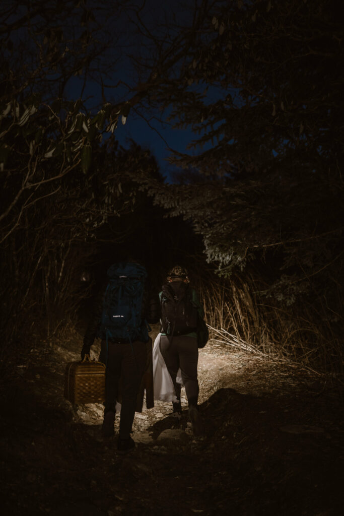 A couple hikes in the dark up a mountain using headlamps in the early morning.