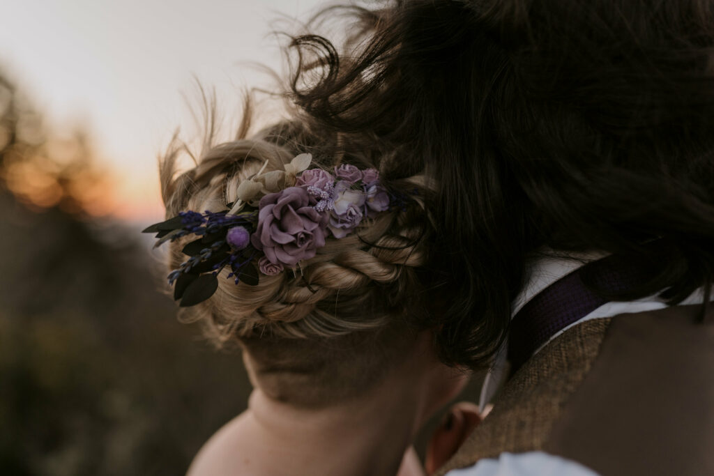 Closeup photo of flowers in a bride’s hair at sunrise elopement session.