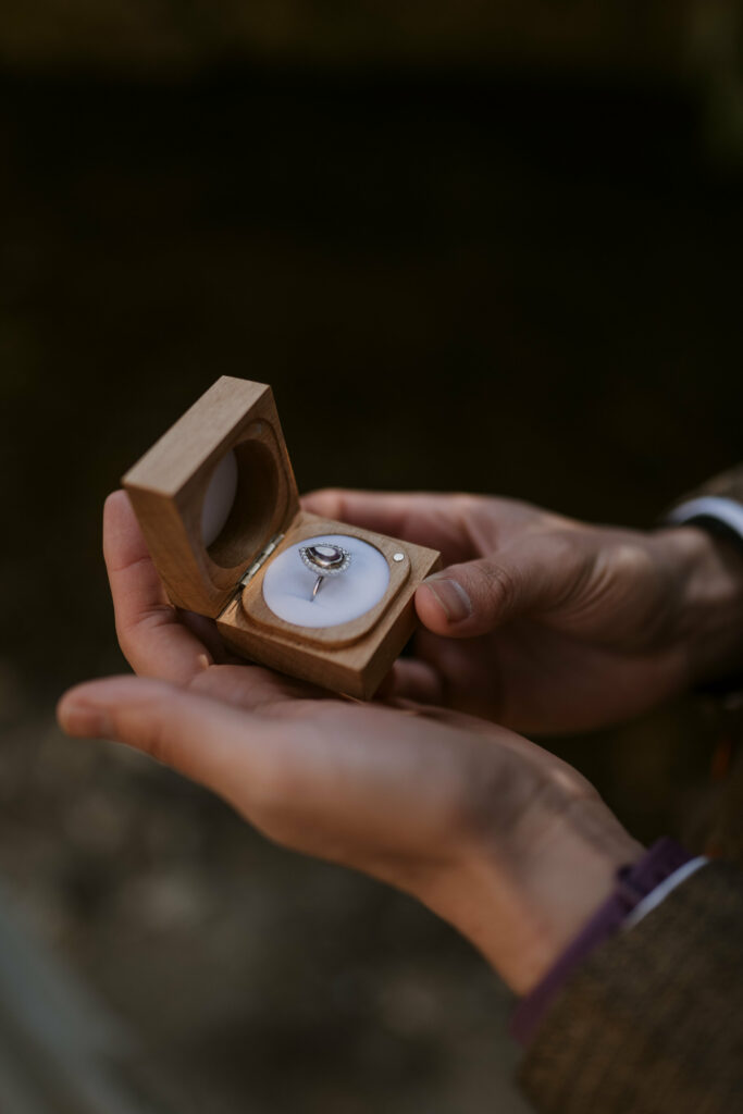 Man holds his wife’s wedding ring in a wooden box.