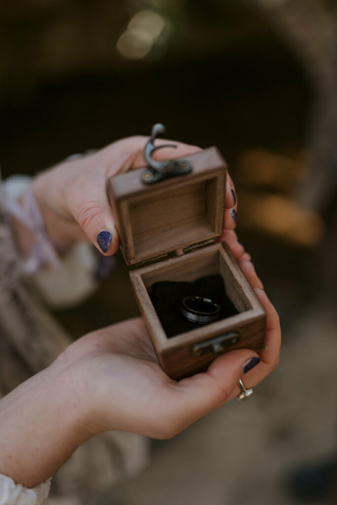 Woman holds her husband’s wedding ring in a wooden box.
