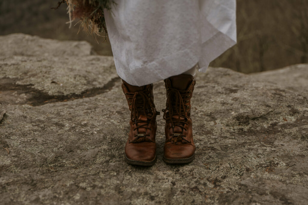 A close-up picture of hiking boots worn underneath a wedding gown.