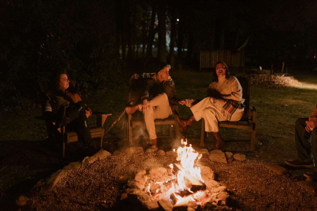 People sit around a fire with friends in the Blue Ridge Mountains to celebrate an elopement.