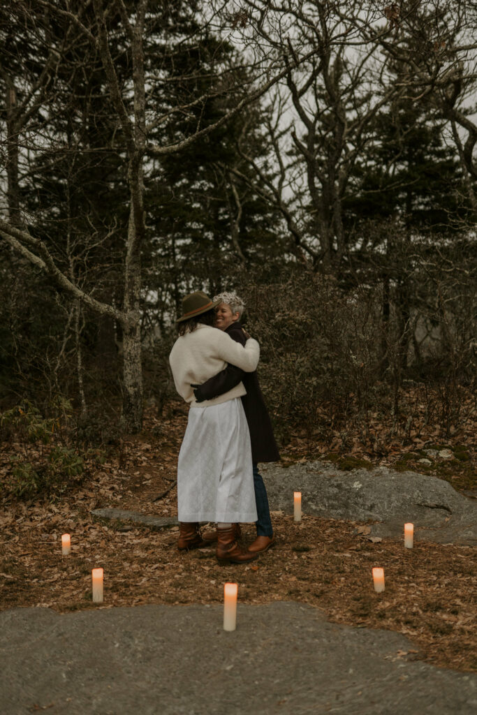 A couple dances on top of a mountain surrounded by candles after getting married.