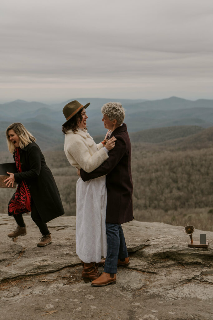 A couple excitedly embraces after their elopement on top of a mountain.