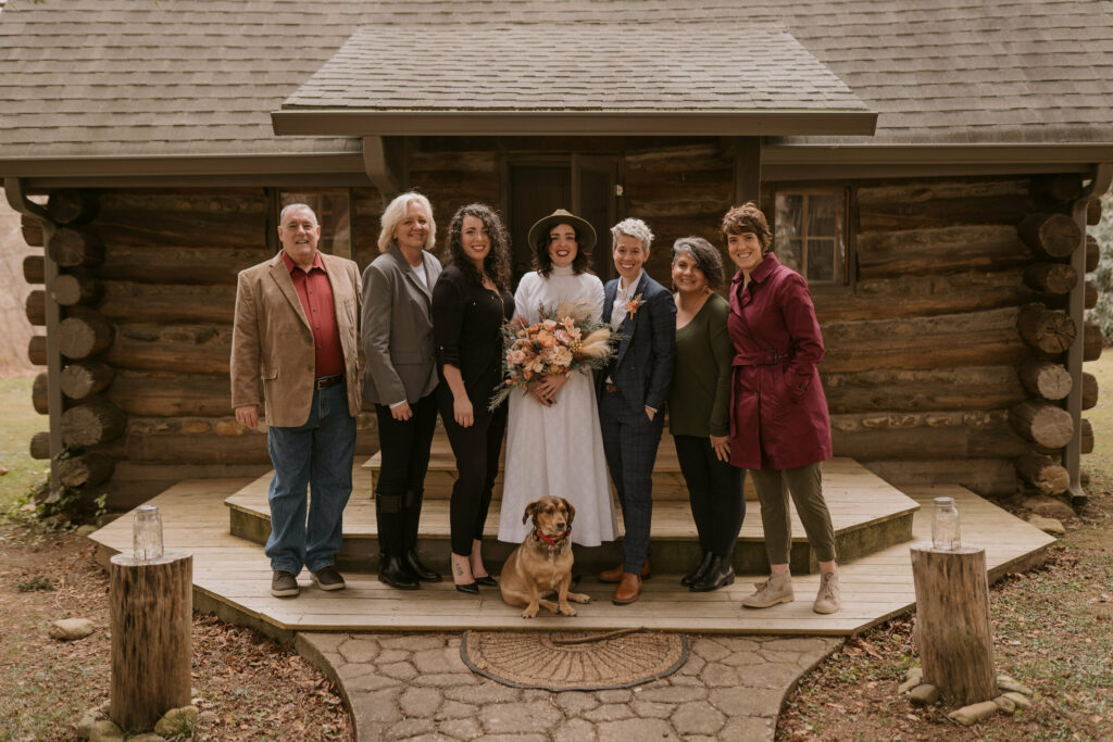 A formal family wedding portrait with a dog in North Carolina outside a log cabin.