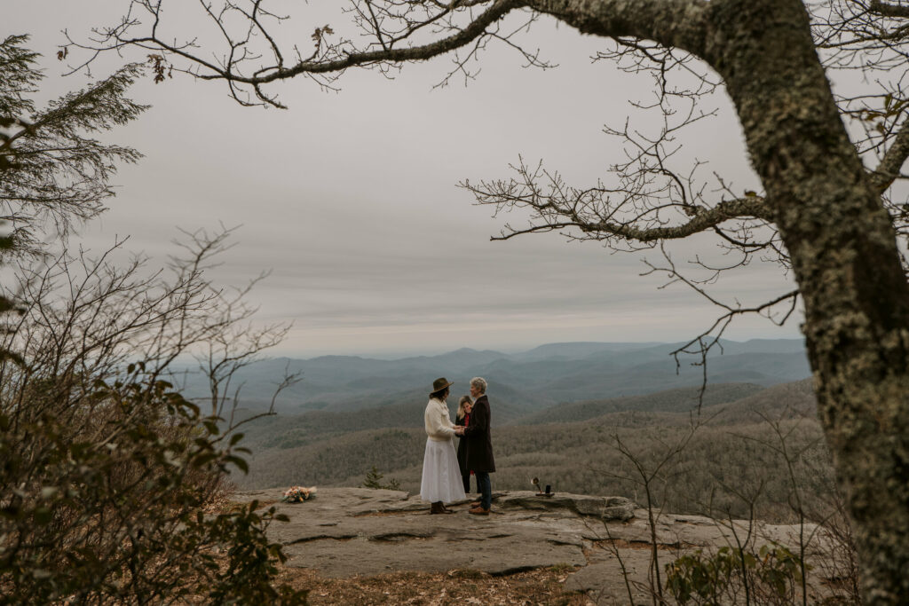 A couple stands on top of a mountain during an intimate elopement ceremony in western NC.