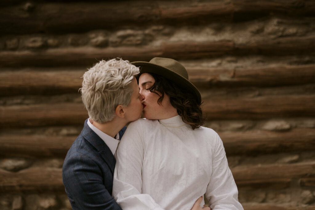 A couple kisses outside cabin during wedding portraits in western NC.