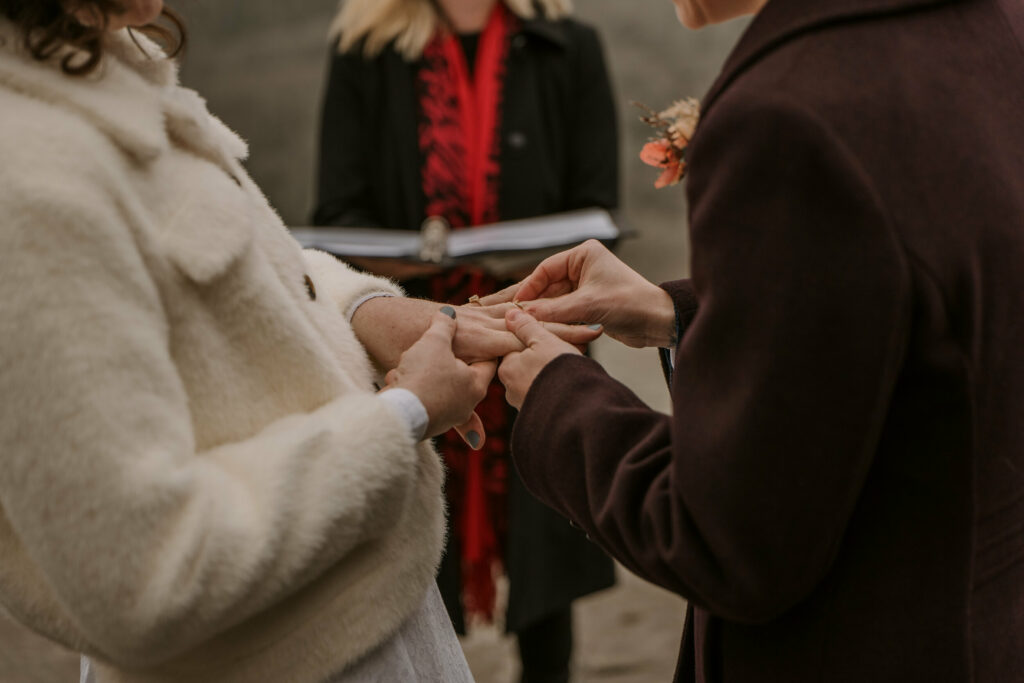 Hands exchanging wedding rings during mountain elopement in NC