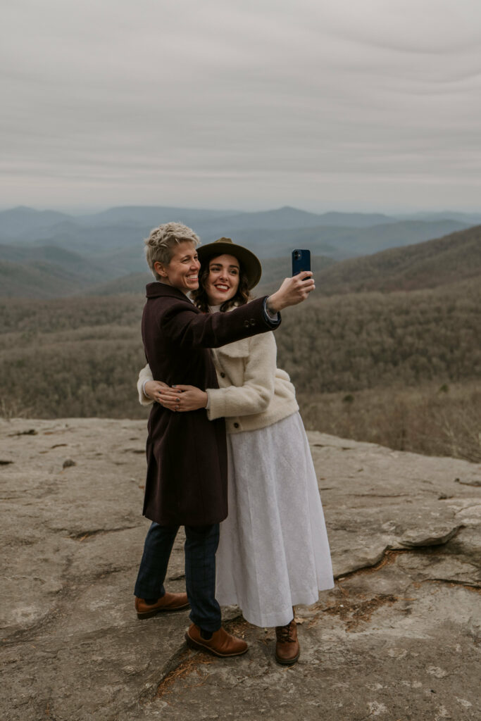 A couple takes a selfie on top of a mountain after their adventure elopement in NC.