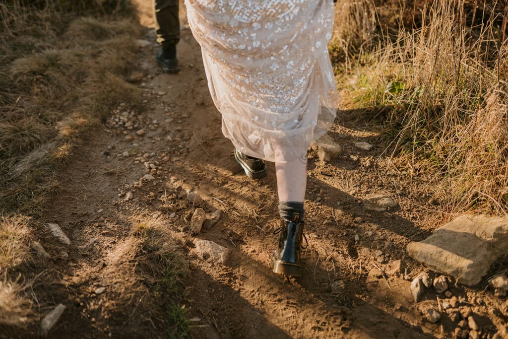 a person with a sparkly dress on is walking on a dusty path with doc marten shoes and a sparkly dress.