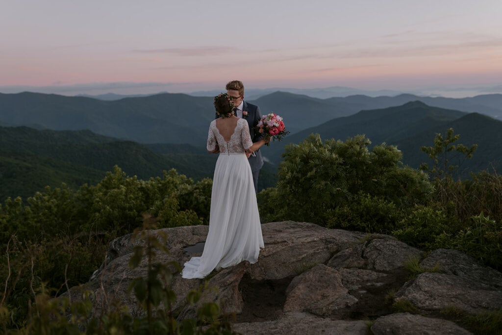 A wedding couple is kissing on a mountain right before sunrise in one of the best places to elope in NC.