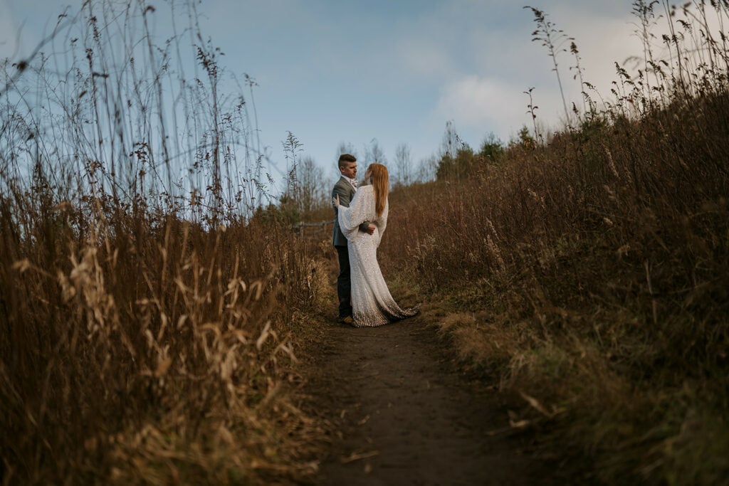A couple has their first dance for their elopement in the middle of the trail, surrounded by tall grass, at Max Patch.