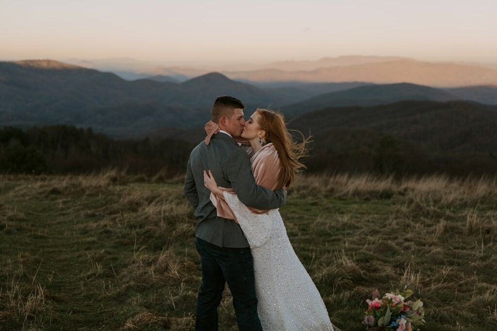 A couple has their first kiss as a married couple during their elopement on max patch at sunrise.