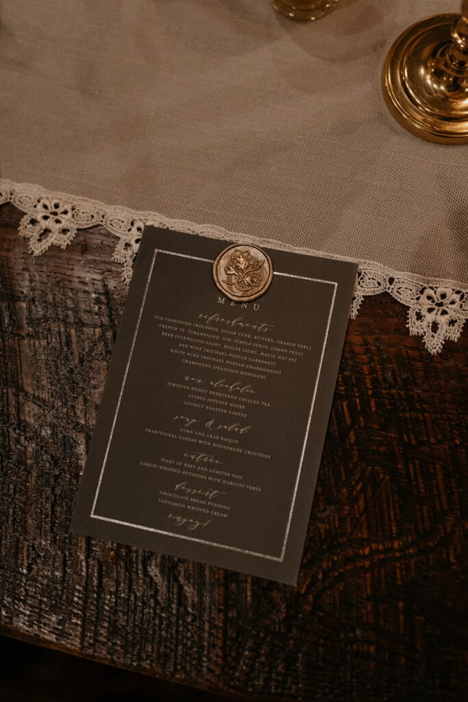 A detailed menu designed in a lovely way for a wedding dinner party on a wooden table with lace runner. 